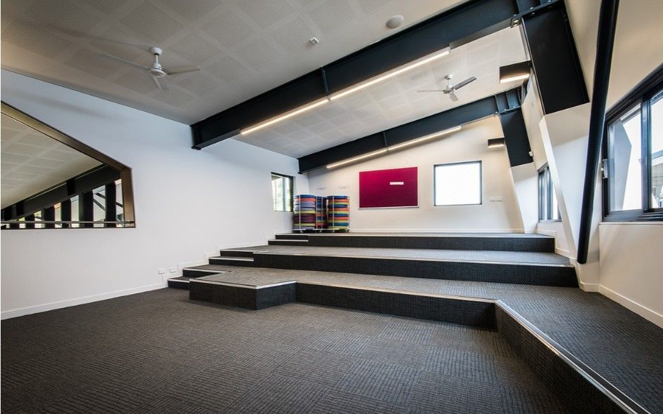 A Modern Classroom With Tiered Seating, Gray Carpet, White Walls, and Black Support Beams — BOLD Architecture + Interior Design In Mackay, QLD