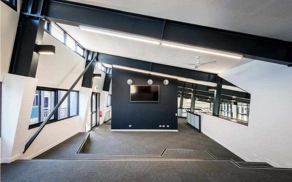 Modern Office Interior With Angled Beams, Dark Blue Wall With TV, Carpeted Floor, and Windows — BOLD Architecture + Interior Design In Mackay, QLD