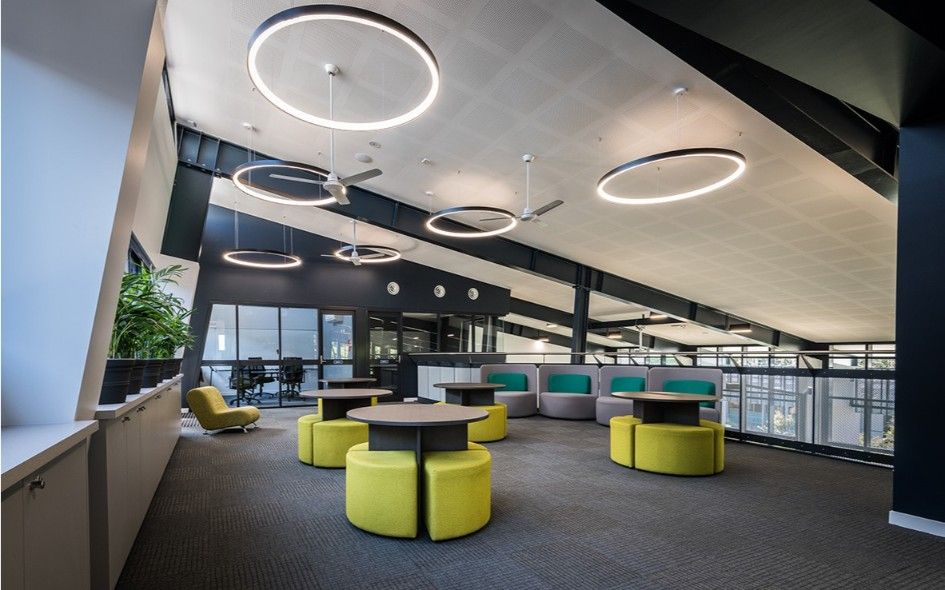 Modern Lounge Area With Yellow Ottomans, Round Tables, and Circular Lights on a Sloped Ceiling — BOLD Architecture + Interior Design In Mackay, QLD