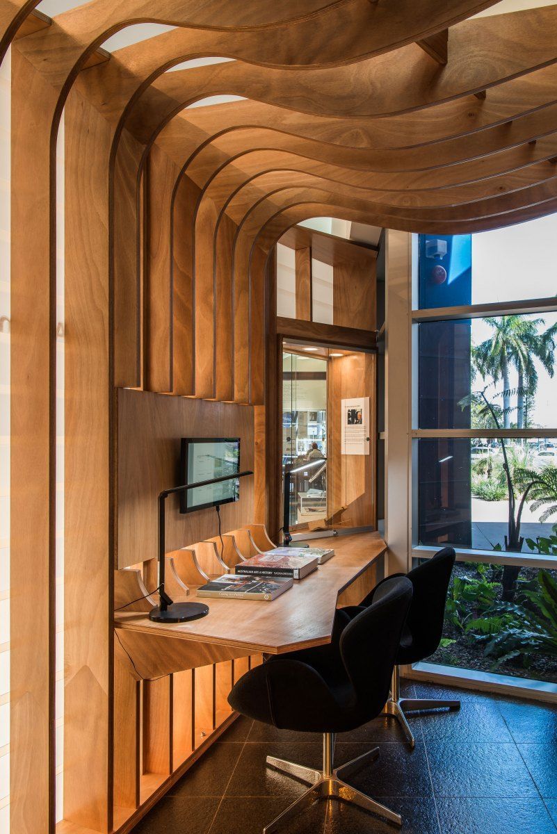 A Wooden Desk With a Black Chair is Built Into a Curved Wall. Sunlight Streams Through a Window — BOLD Architecture + Interior Design In Mackay, QLD