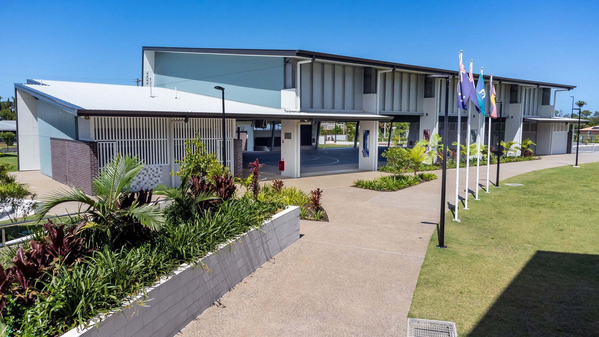 Modern Two-story Building With a Light Blue Facade and Flags in Front — BOLD Architecture + Interior Design In Mackay, QLD