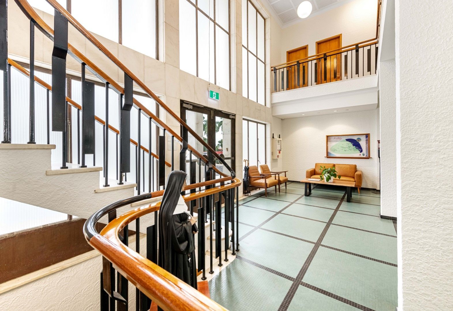 Wooden Staircase in a Bright Lobby With Seating Area and Artwork — BOLD Architecture + Interior Design In Mackay, QLD