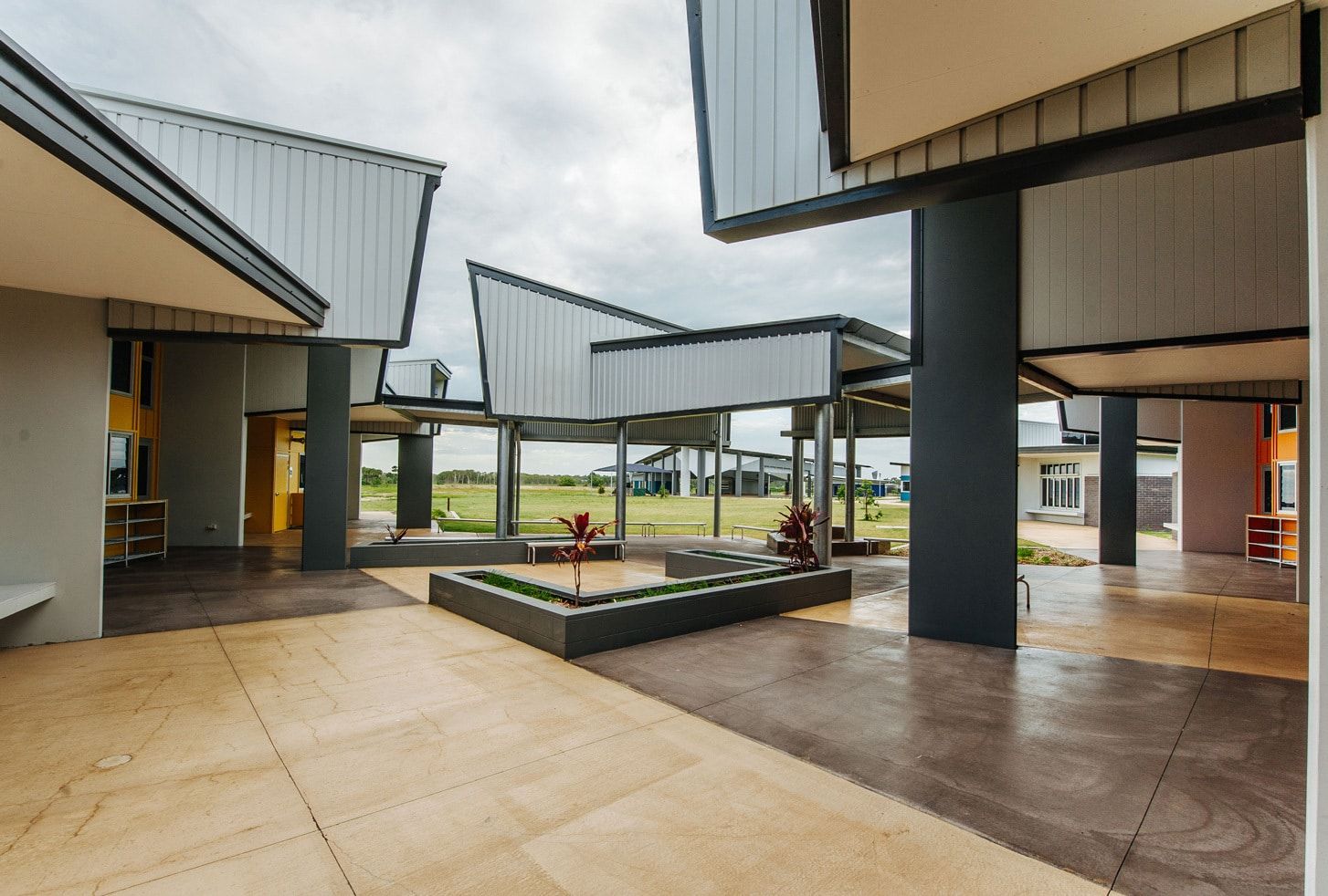 Modern Building Courtyard With Angular Rooflines and Brown and Grey Paving — BOLD Architecture + Interior Design In Mackay, QLD