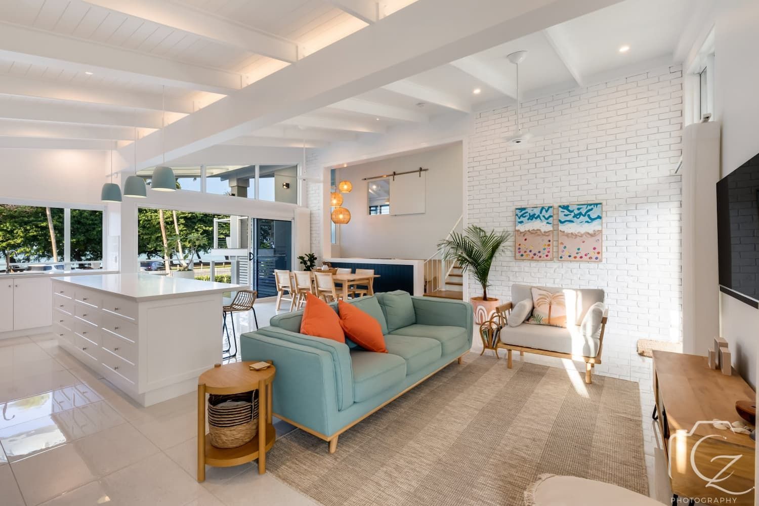 Spacious, Bright Living Room with Turquoise Couch, White Brick Wall, and Open Kitchen — BOLD Architecture + Interior Design In Mackay, QLD
