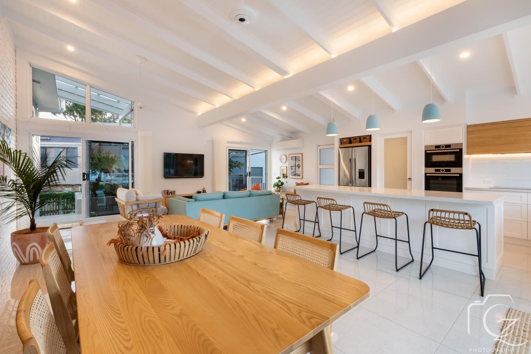 Open-Concept Kitchen and Dining Room with Light Wood Furniture, White Walls, and Aqua Accents — BOLD Architecture + Interior Design In Mackay, QLD