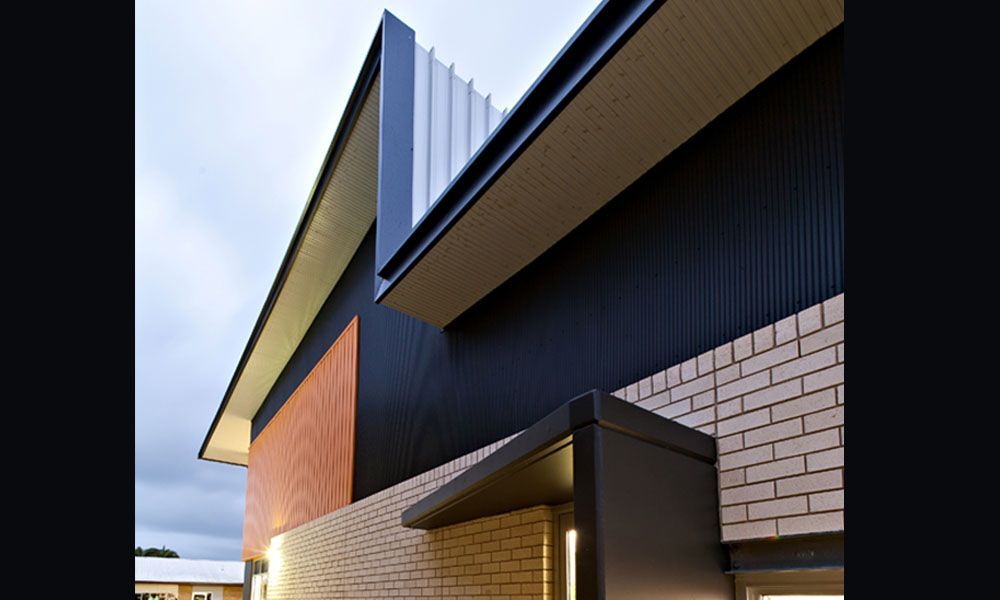 Modern Building Exterior With Black Corrugated Metal Siding, Tan Brick, and Angled Roof Lines — BOLD Architecture + Interior Design In Mackay, QLD