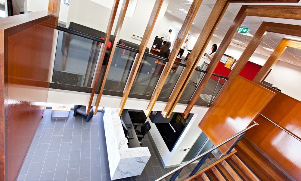 View From Above of a Modern Lobby With Wooden Beams, Stairs, Reception Desk, and Tile Flooring — BOLD Architecture + Interior Design In Mackay, QLD