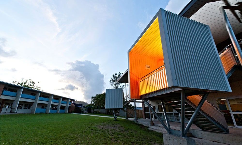 Modern School Buildings With Orange and Grey Accents Stand on a Green Lawn Under a Cloudy Sky — BOLD Architecture + Interior Design In Mackay, QLD