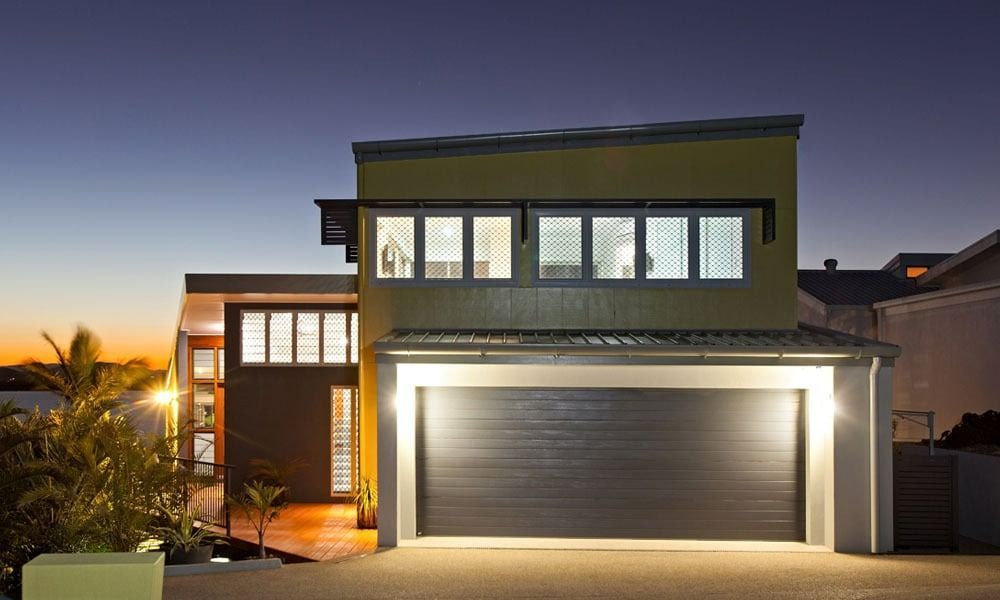 Modern House Exterior at Dusk, with Garage Door and Lit Windows — BOLD Architecture + Interior Design In Mackay, QLD