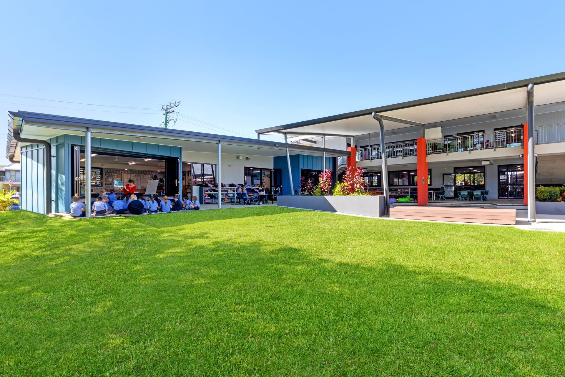 A Grassy Lawn Leads to a School With Blue and Gray Buildings — BOLD Architecture + Interior Design In Mackay, QLD