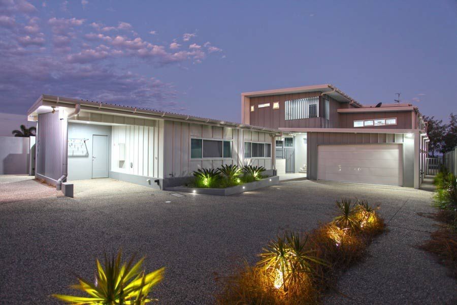 A Large House With A Garage And A Driveway Is Lit Up At Night — BOLD Architecture + Interior Design In Mackay, QLD