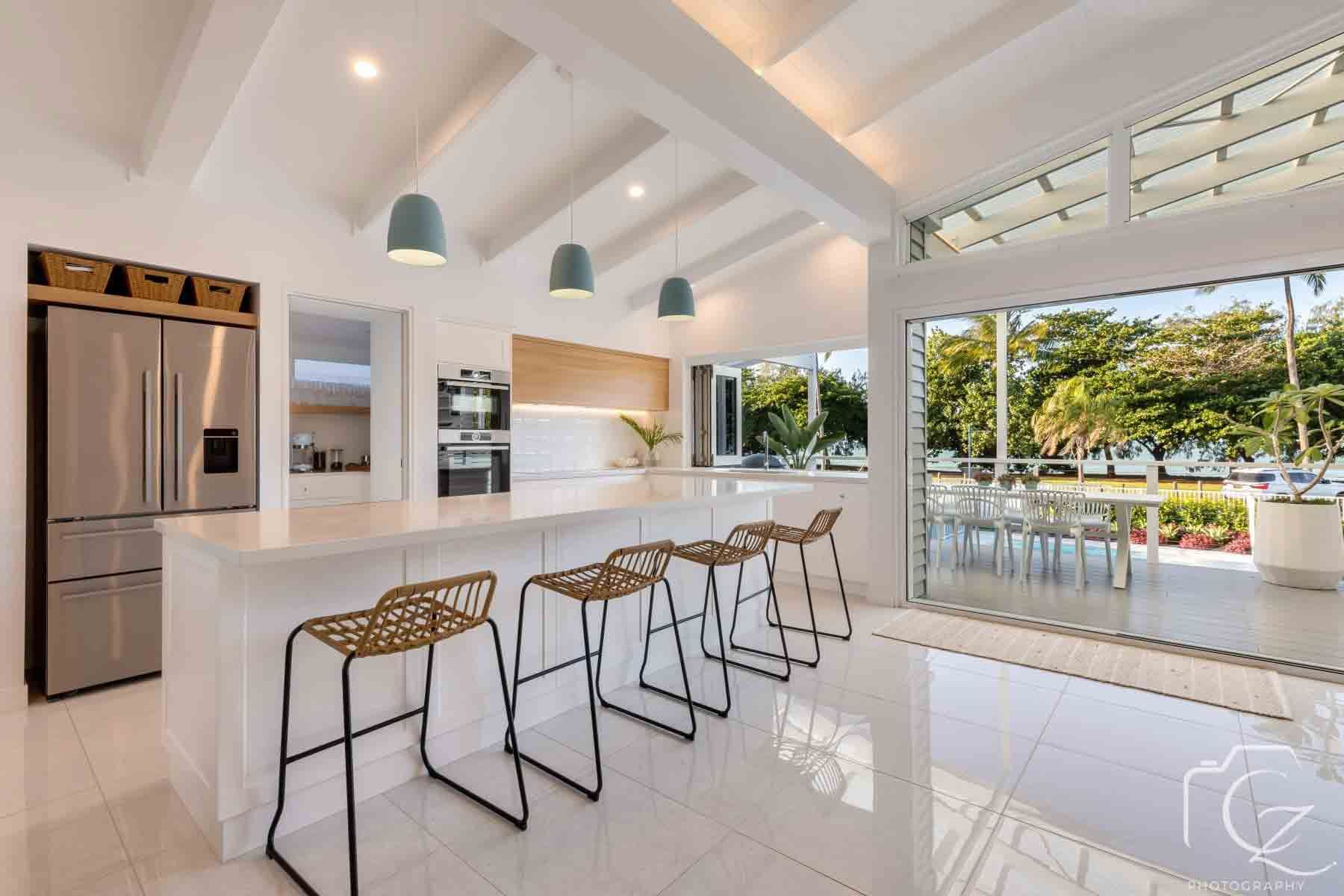 A Kitchen With A Large Island And A Sliding Glass Door — BOLD Architecture + Interior Design In Whitsundays, QLD