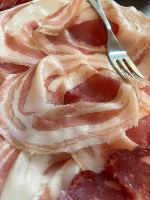 Salame affettato, carne rosso-marrone con macchie bianche, primo piano.