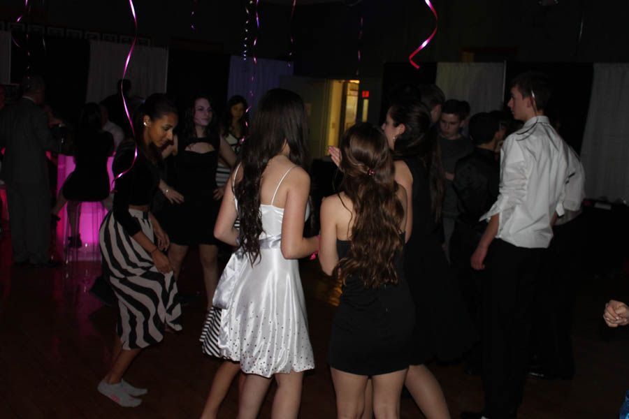 People dancing at a party in a decorated room with pink streamers.