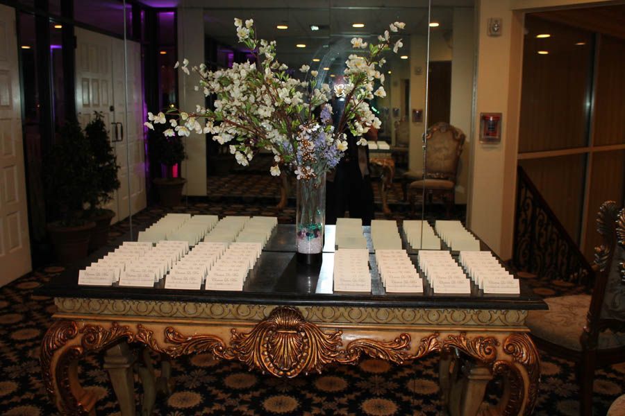 A fancy table with name cards and flowers, inside a decorated hall.