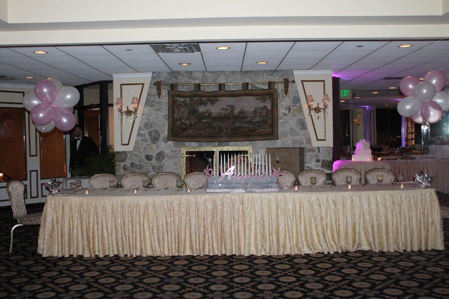 Formal event room with a long decorated table, balloons, and a stone fireplace.