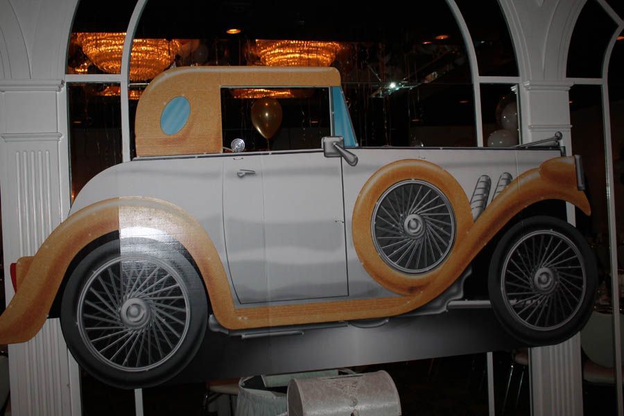 Cardboard cutout of a classic car, light and dark tan with black wheels and a white body.