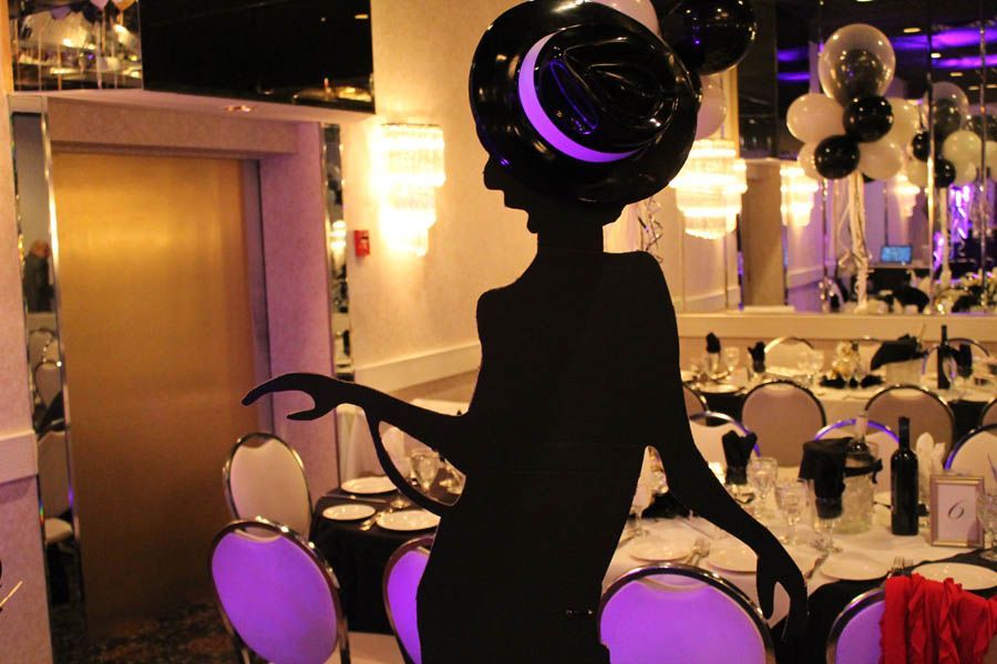 Silhouette decoration of a woman in a hat, at a table set for a party, with black and white balloons.