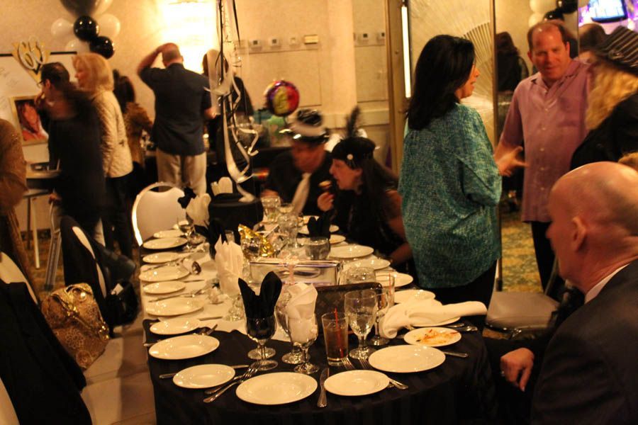 People gathered around a festively decorated table; a party setting with black and gold decor.