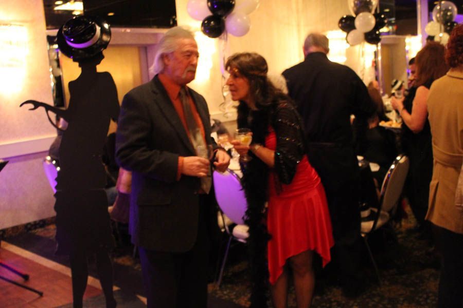 Man in suit talking to woman in red dress at event with decor.