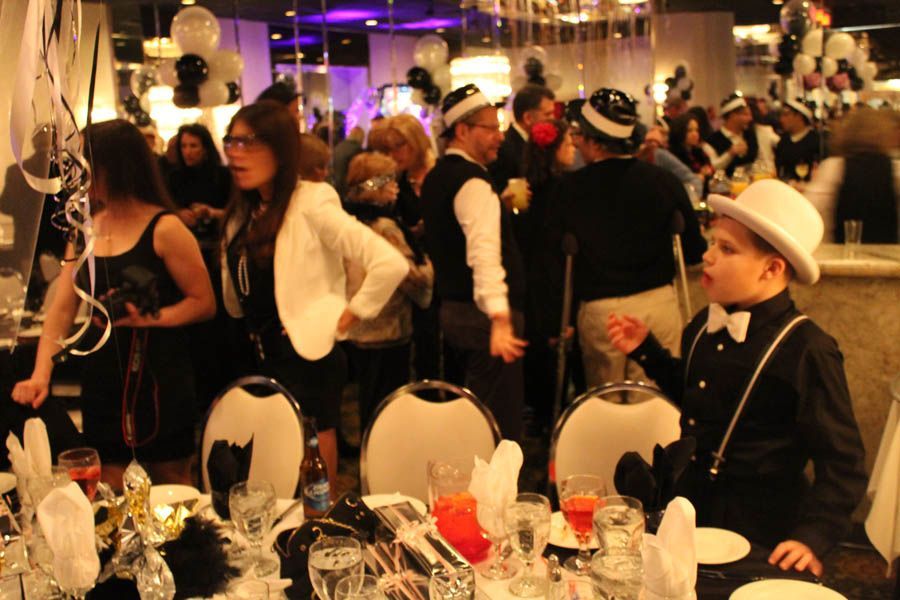 People at a party, some wearing hats and bow ties. Black, white, and red decor.
