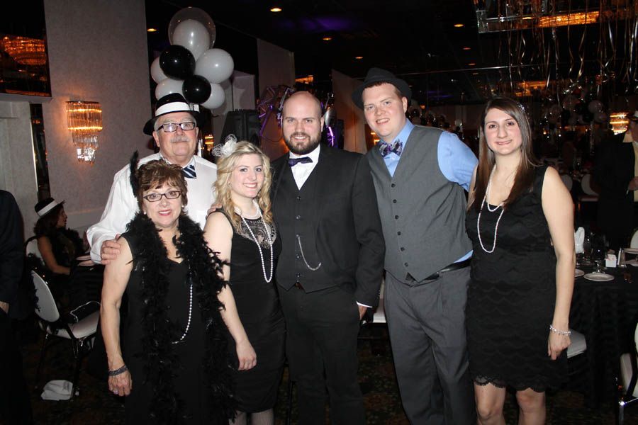 Group dressed in 1920s attire at a party, including hats, feather boas, and pearls, indoors.