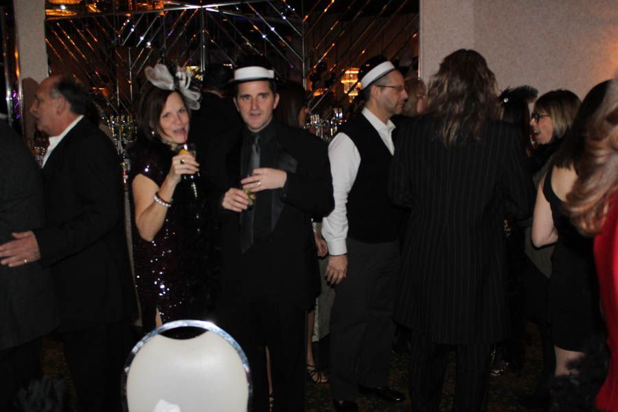 People in formal attire at a party; some are wearing sailor hats.