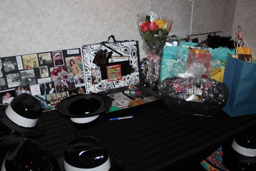 A table with gifts, flowers, hats, and photos, likely for a celebration or event.