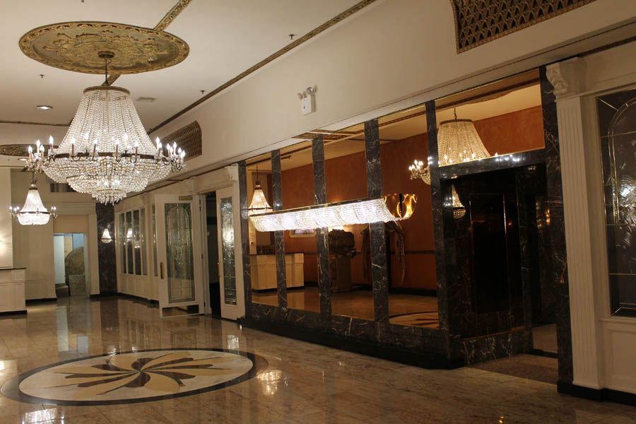 Ornate hotel lobby with chandeliers, marble floors, and mirrored accents.