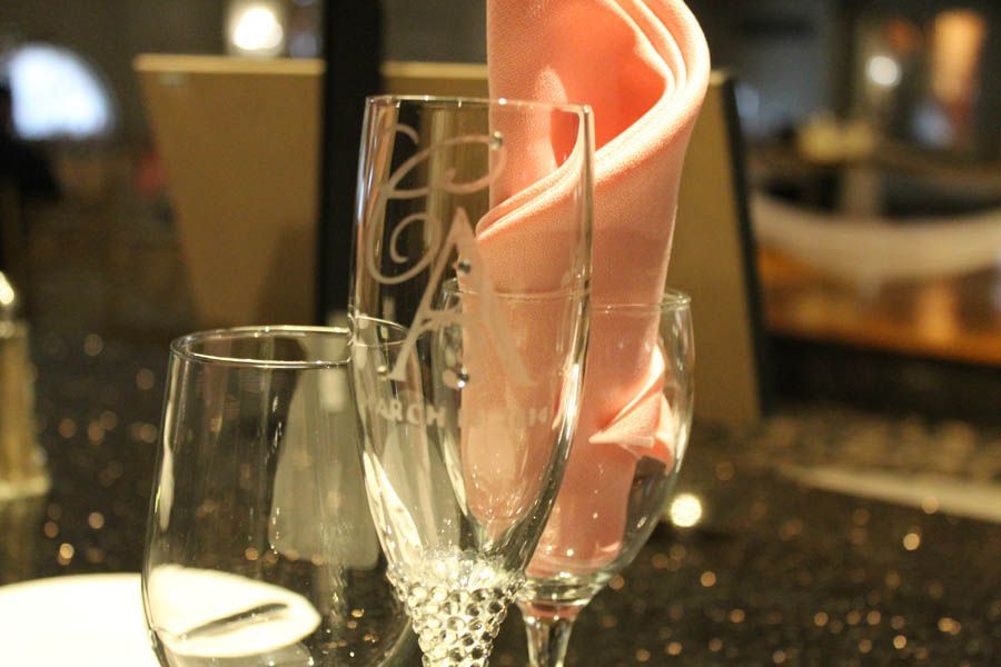 Close-up of three clear glasses with a pink folded napkin; set on a table.