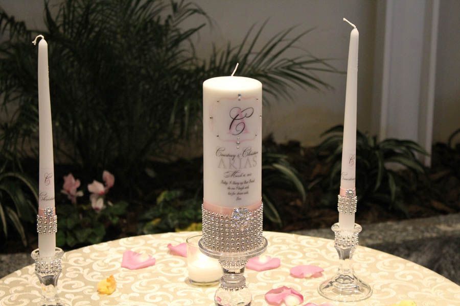 Wedding unity candle set with pink and silver embellishments on a table with petals.