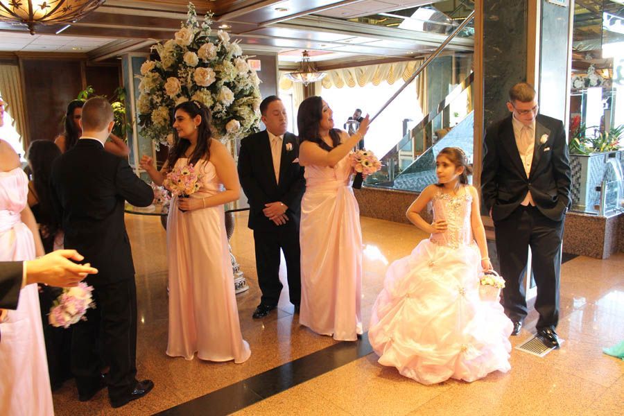 Wedding party in a hotel lobby, wearing formal attire, some holding bouquets.