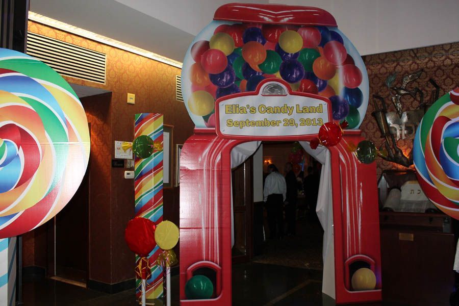 Candy-themed entrance: giant gumball machine archway, lollipop decorations, and colorful balloons lead into an event.