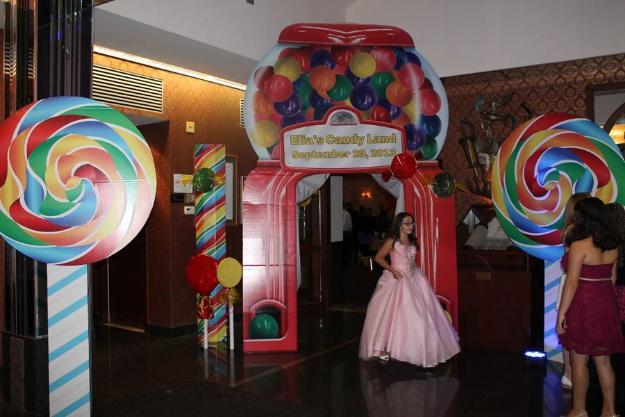 Entrance decorated with giant lollipops, candy-themed archway, girl in pink dress posing.