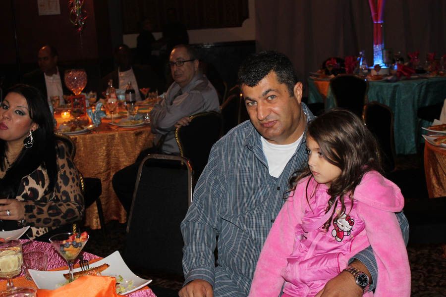 Man holding child at a festively decorated event with seated people at tables.