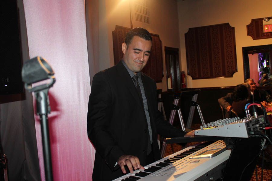 Musician in a suit playing a keyboard at an event.