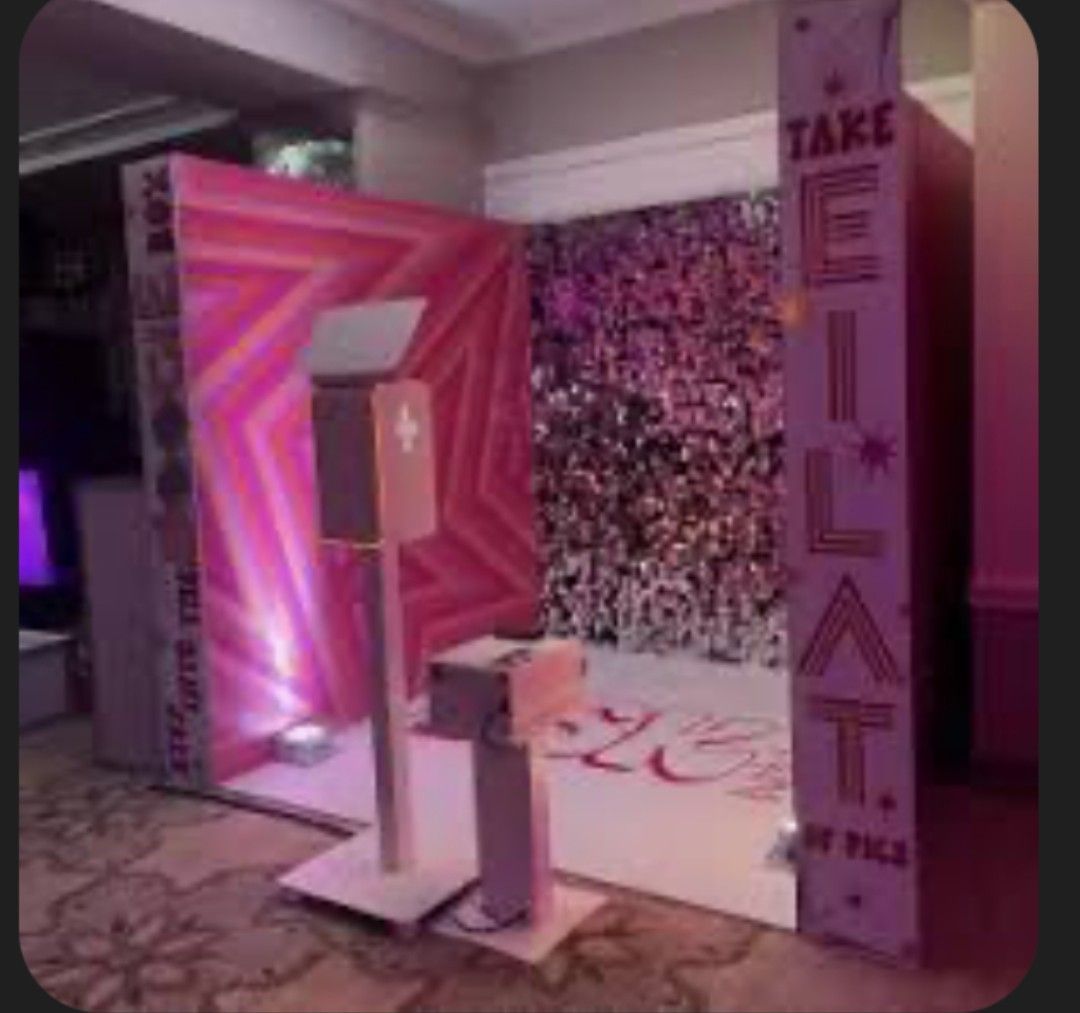 Photo booth with pink star backdrop, camera, and