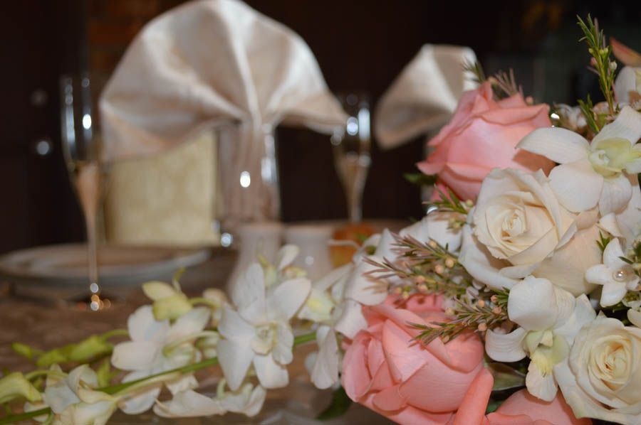 Close-up of a table setting with pink and white roses, champagne flutes, and a folded napkin.