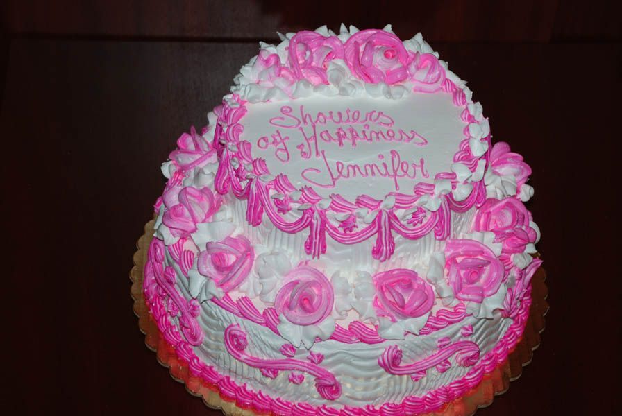 Two-tiered cake with pink and white frosting, decorated with roses. 