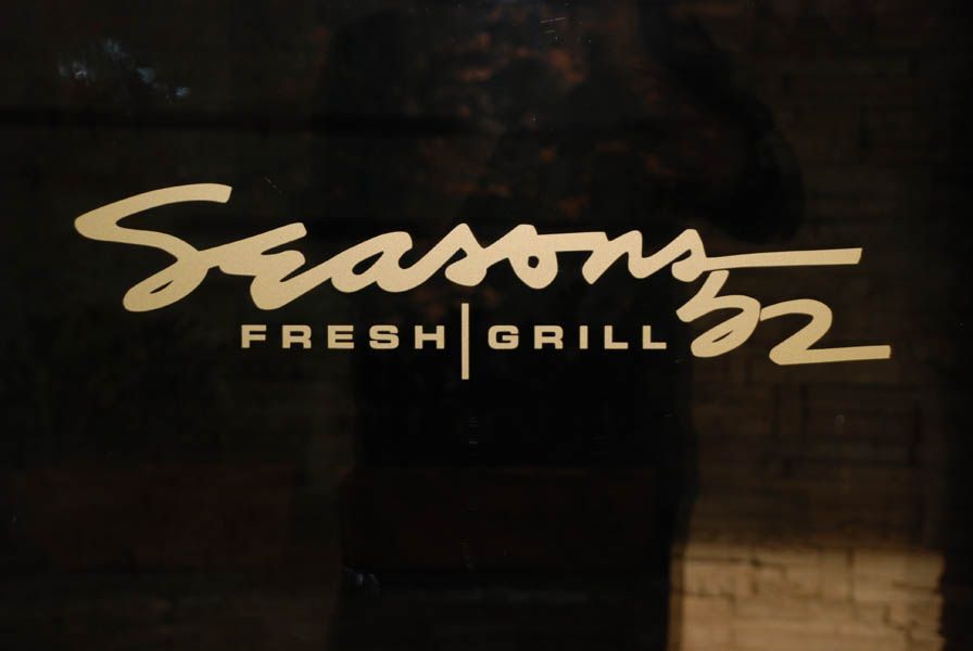 Seasons 52 Fresh Grill logo, gold lettering on a dark surface.