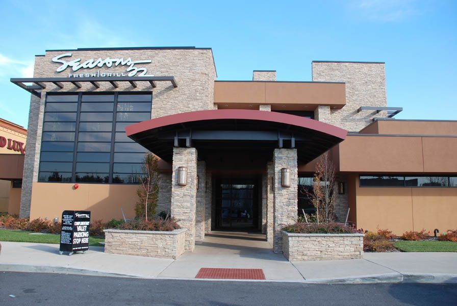 Seasons 52 restaurant entrance with stone facade, dark canopy, and large windows.
