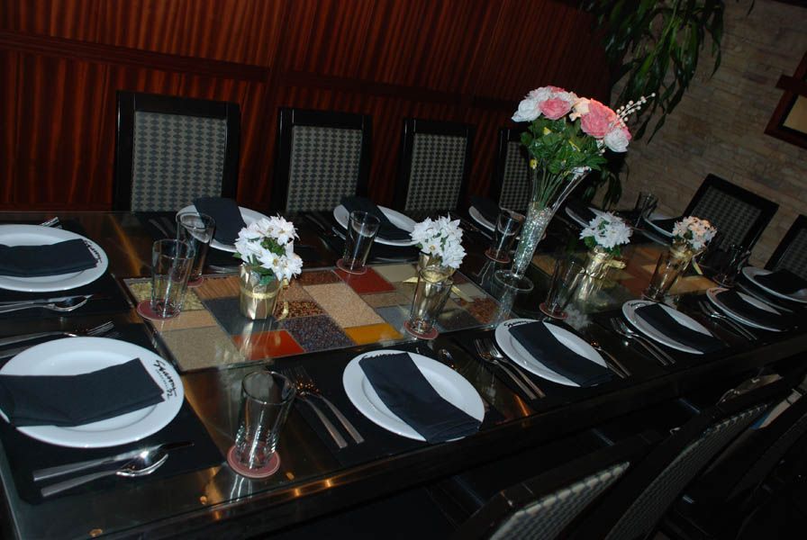 Long dining table set with place settings, centerpieces, and black napkins.