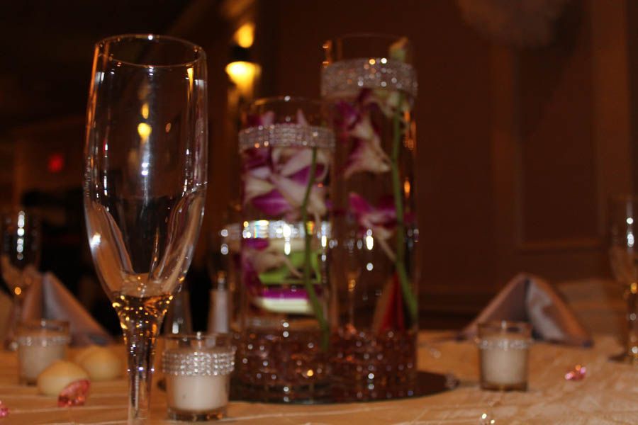 Champagne glass at a wedding table with floral centerpieces, candles, and pink accents.