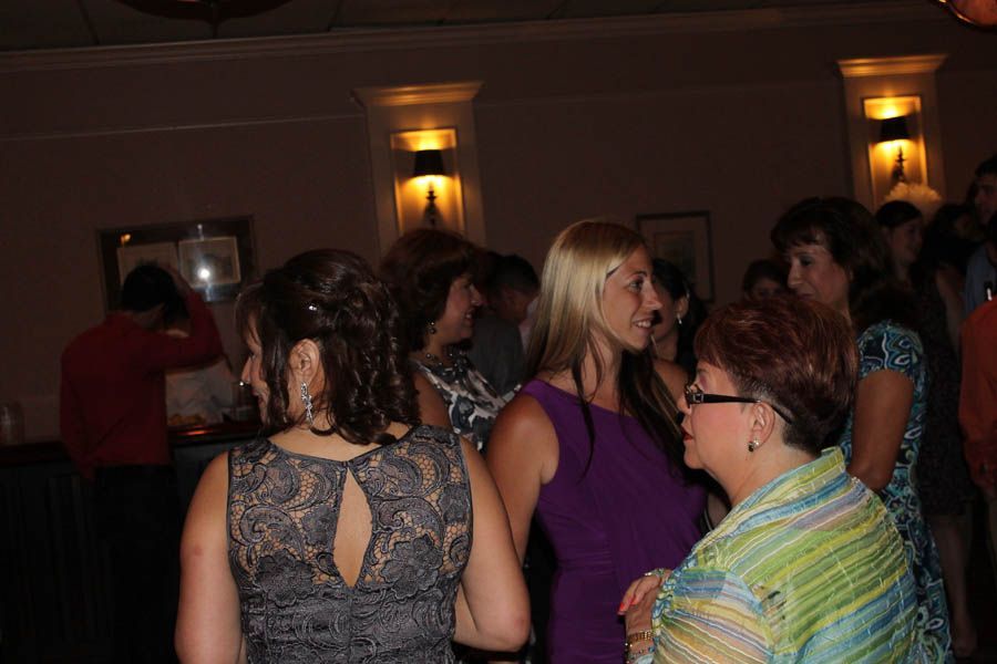 Group of people socializing in a dimly lit room, some wearing dresses.
