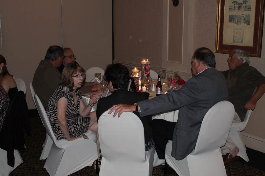 People seated around a table at an event, with center candles and a picture on the wall.