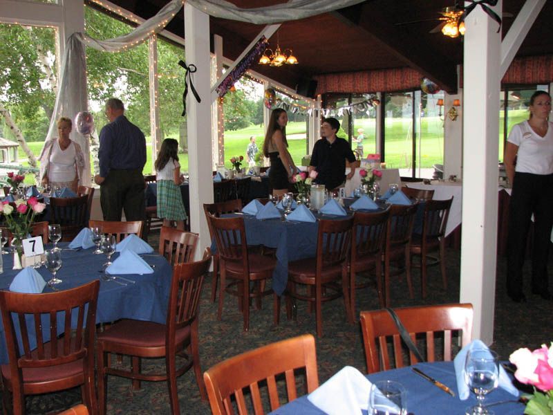 Party venue with tables set for guests, decorations, and people.