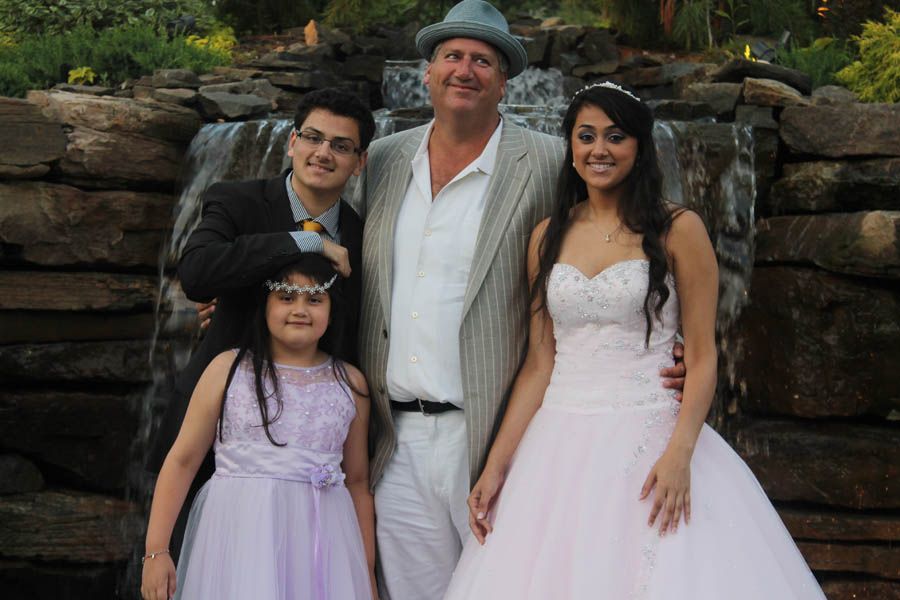 Family posing in front of a waterfall: woman in formal dress, man in hat, two children.