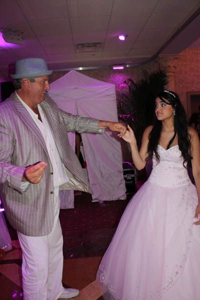 Man in suit dances with a woman in a ballgown at an event.