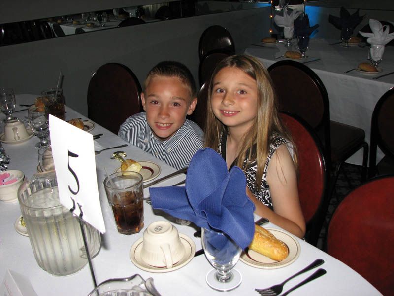 Two children smiling at a table in a restaurant. Table number 5.