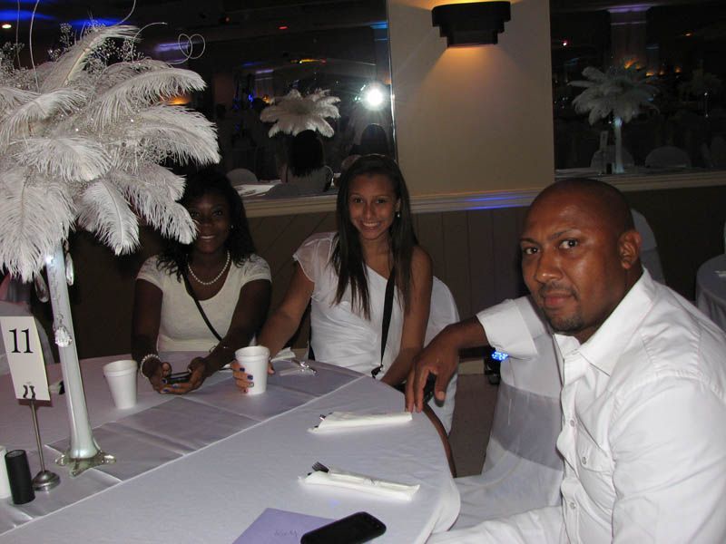 Three people at a table, two women and a man. White tablecloth, centerpieces, soft lighting.